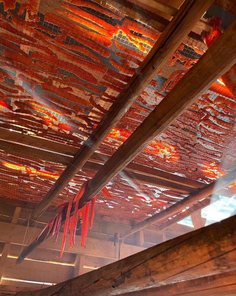The inside of a smokehouse in Gitsegukla First Nation. Salmon strips are hung on trays and over beams, where they are slowly rotated over a slow smoking fire. Photo: Janna Wale. 